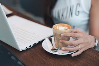 Woman Holding Latte Coffee Cup Next to Laptop