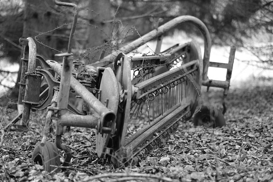 Abandoned vintage farm machinery in black and white
