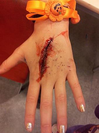 Child's hand with fake bloody wound and Halloween pumpkin hair bow