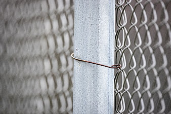 Close-up of chain link fence post with wire tie