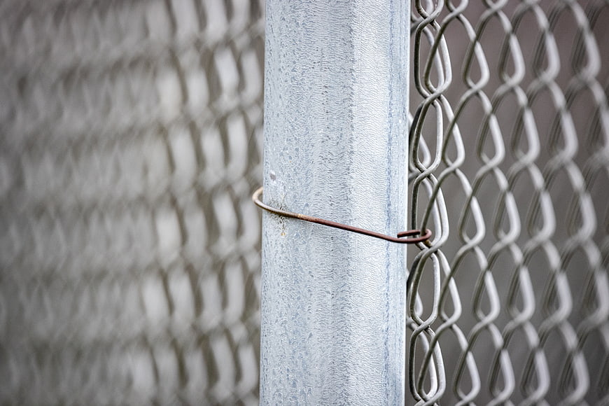 Close-up of chain link fence post with wire tie