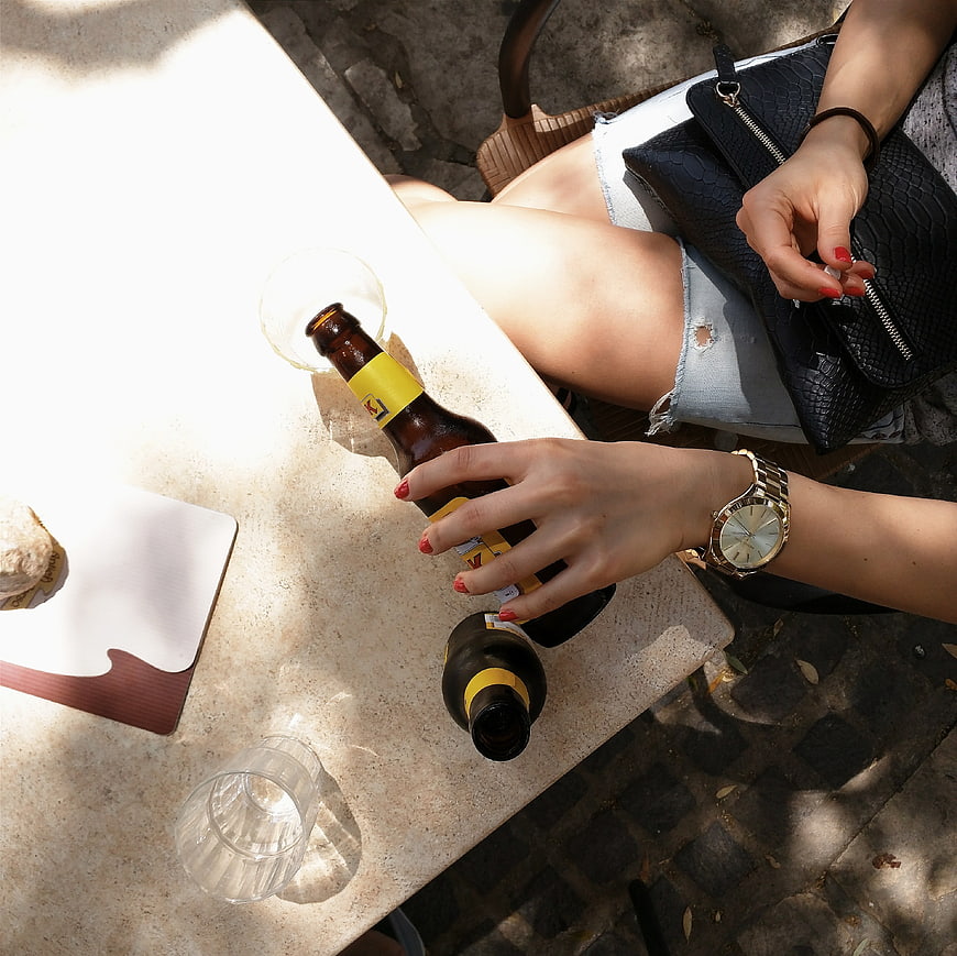 Top view of woman holding beer bottle at outdoor cafe