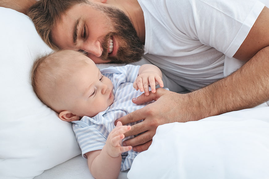 Happy Father Cuddling with Baby in Bed