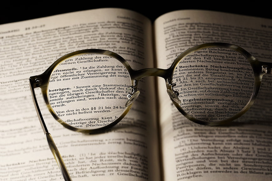 Reading glasses resting on open book pages with German legal text