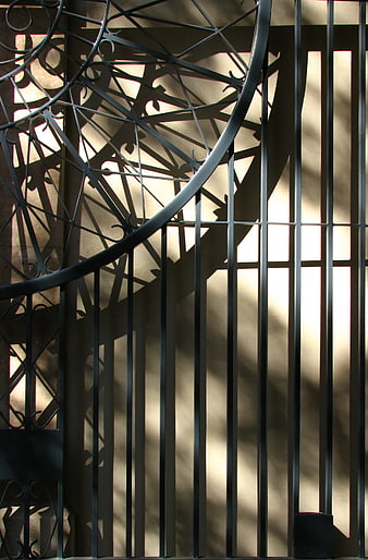 Abstract shadows of wrought iron gate on beige wall