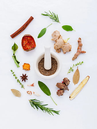 Flat lay of fresh herbs, spices, and mortar on white background
