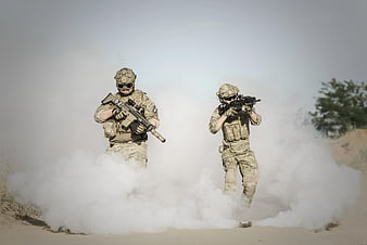Two soldiers advancing through smoke in desert tactical training