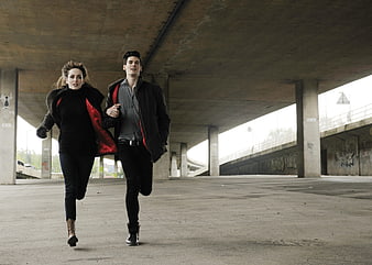 Young couple running together under concrete overpass
