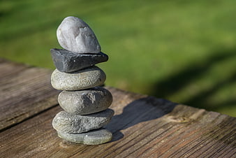 Stacked stones on wooden surface with green background
