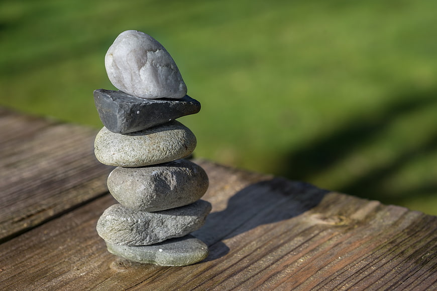 Stacked stones on wooden surface with green background