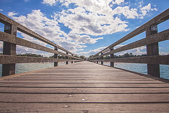 Wooden Pier Leading to Beach Under Blue Sky