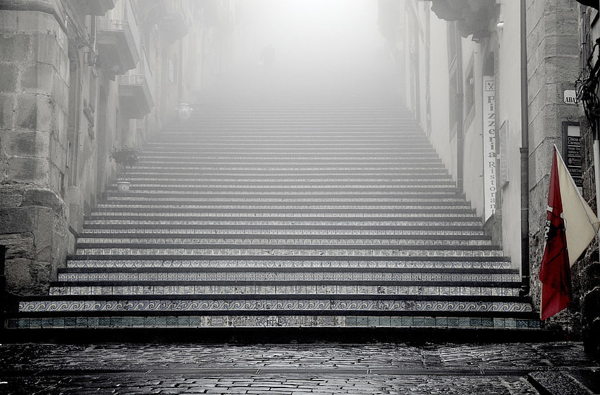 Foggy Stone Staircase in Old European Town with Red Flag