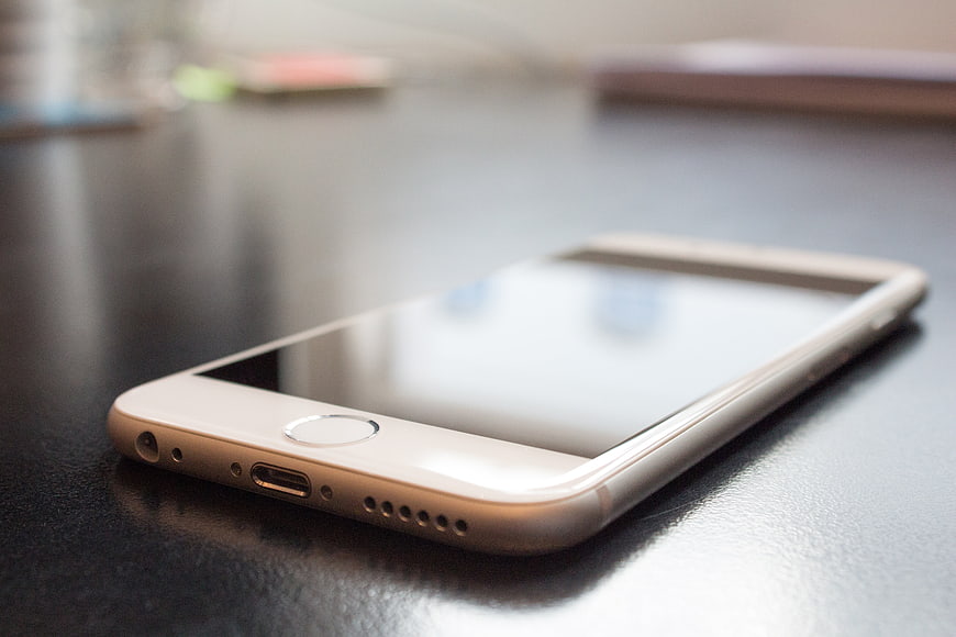 Gold smartphone lying on a dark desk surface