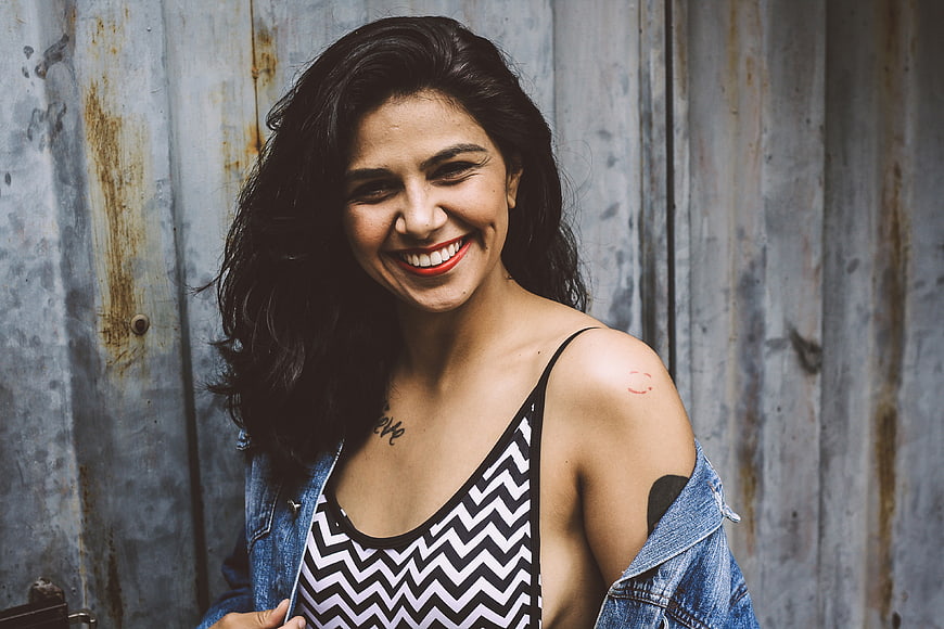Happy Smiling Woman with Tattoos Against Rusty Metal Wall
