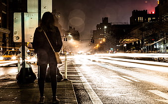 Woman waiting at city bus stop at night with light trails