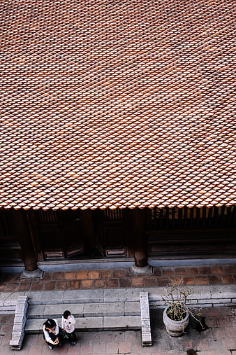 Aerial view of traditional tiled roof with people sitting below
