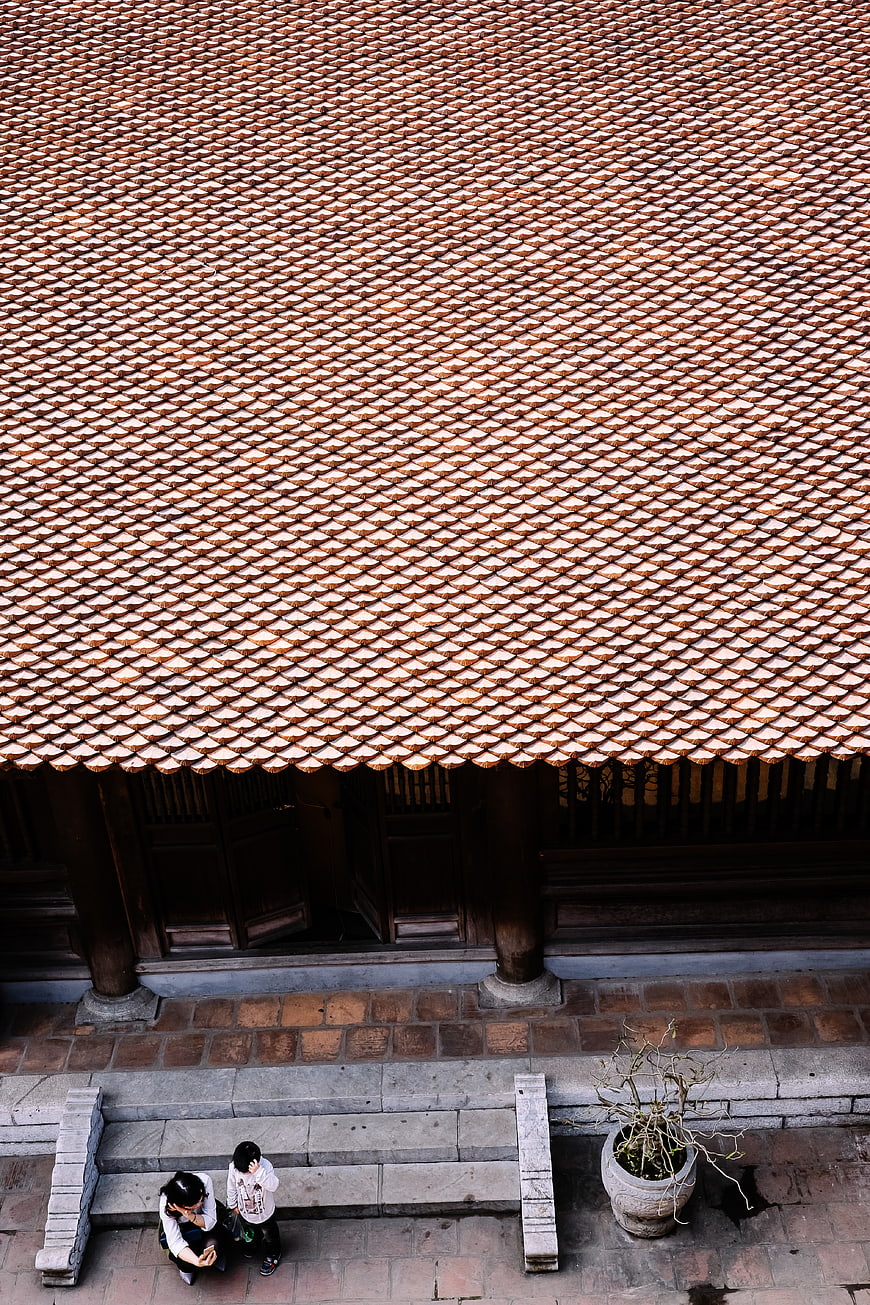 Aerial view of traditional tiled roof with people sitting below