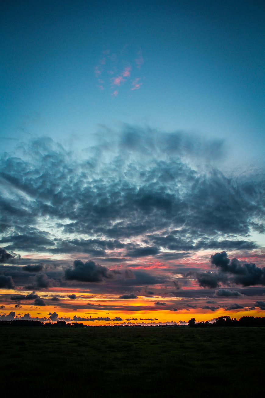 Dramatic sunset sky with colorful clouds over dark field