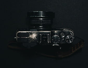 Vintage black camera with leather strap on dark background