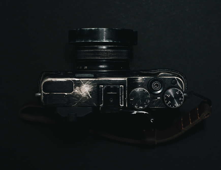 Vintage black camera with leather strap on dark background