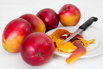 Fresh Red Mangoes with Peels and Knife on White Plate