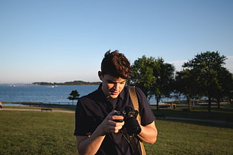 Young Man Reviewing Photos on DSLR Camera in Park