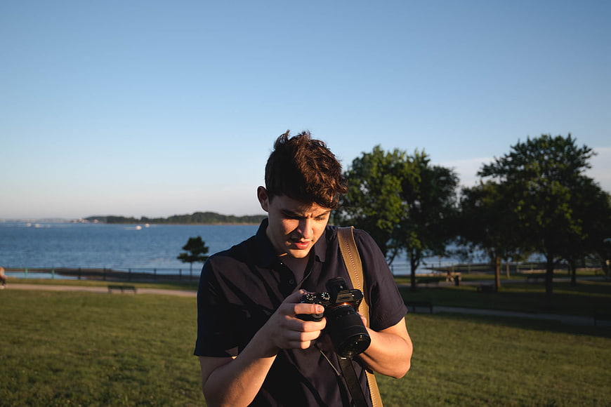 Young Man Reviewing Photos on DSLR Camera in Park