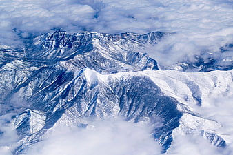 Aerial view of snow-covered mountain peaks above clouds