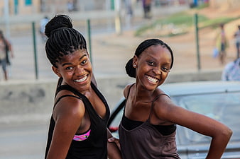 Two smiling young African women with braided hair in an urban setting