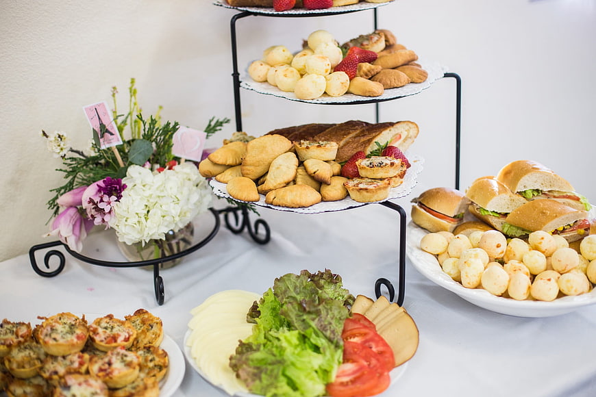 Catering buffet table with sandwiches, pastries, and flowers