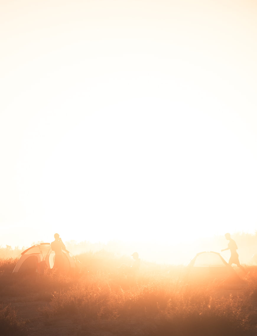 Silhouettes of campers in golden sunrise light