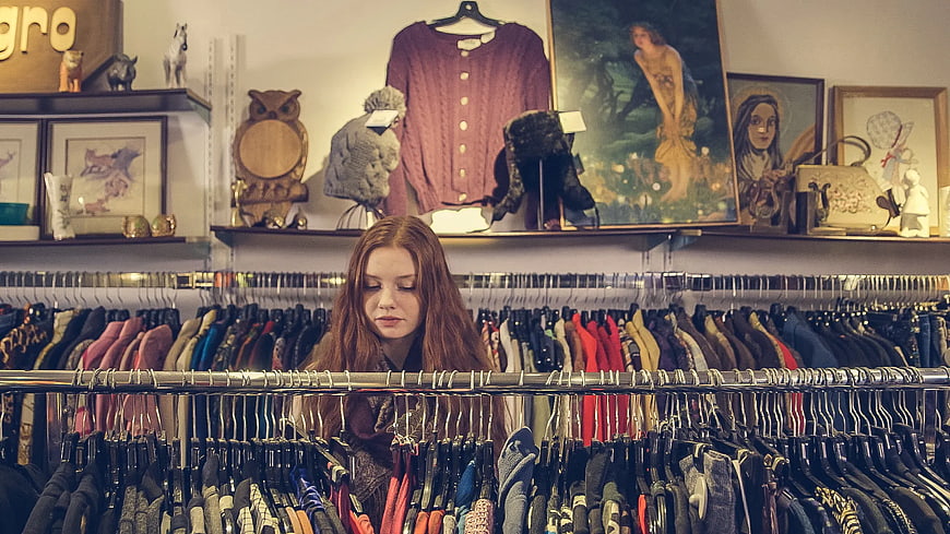 Young woman browsing vintage clothing racks in a boutique
