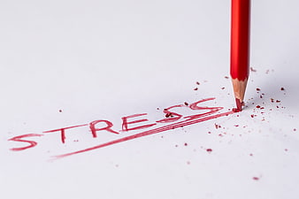 Red pencil writing the word stress on white paper