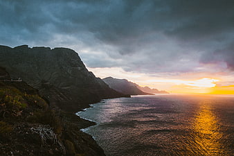 Dramatic Sunset Over Rugged Coastal Mountains and Ocean