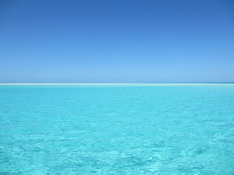 Serene turquoise tropical ocean with clear blue sky horizon