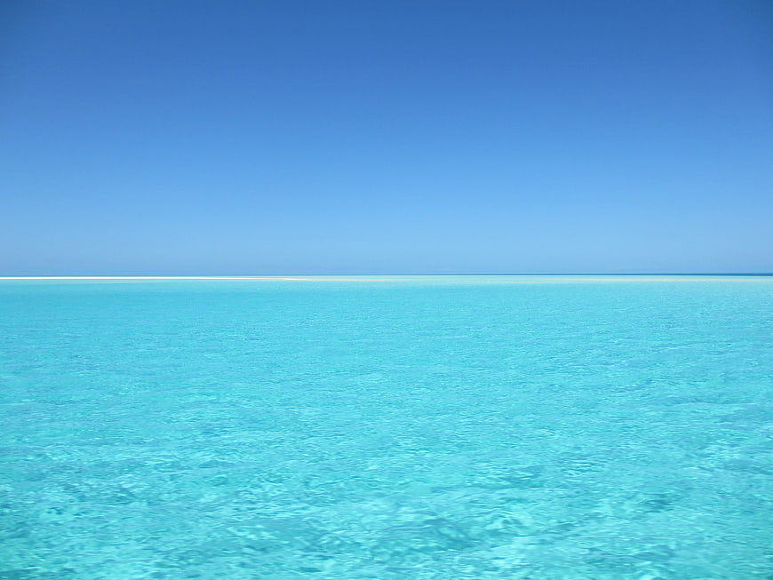 Serene turquoise tropical ocean with clear blue sky horizon