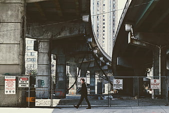 Man walking past construction site under elevated highway