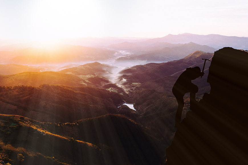 Silhouette of Rock Climber Scaling Cliff at Sunrise