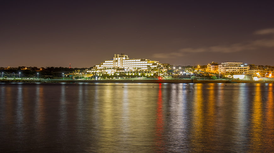 Night view of illuminated coastal resort city skyline with water reflections