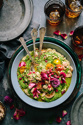 Overhead view of vibrant green herb salad with edible flowers and nuts