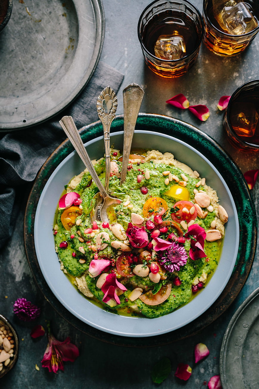 Overhead view of vibrant green herb salad with edible flowers and nuts