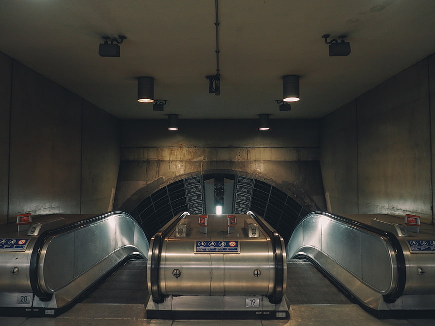 Symmetrical view of empty escalators in a dimly lit underground tunnel