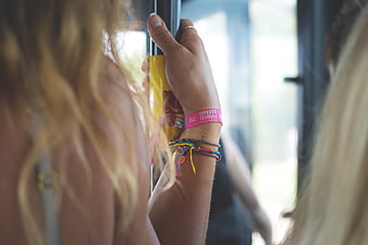 Close-up of hand holding bus pole with festival wristband