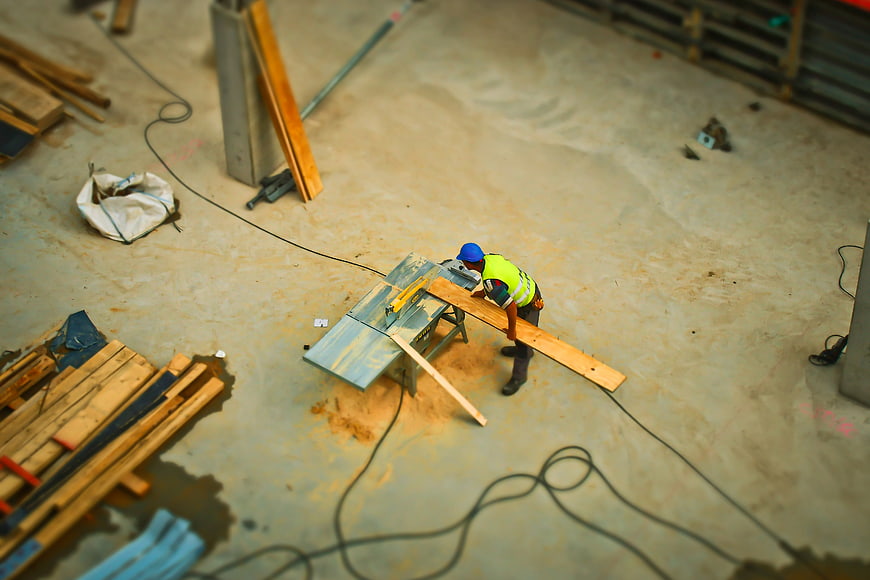 Tilt-shift construction worker cutting wood on a table saw