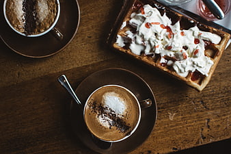 Top view of cappuccino and waffle with cream on wooden table