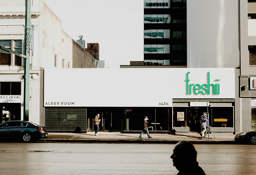 Freshii storefront on a sunny city street with pedestrians