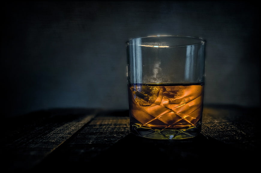 Glass of Whiskey with Ice on Dark Wooden Table