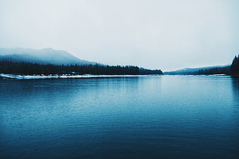 Serene Blue Lake Landscape with Misty Forest Mountains
