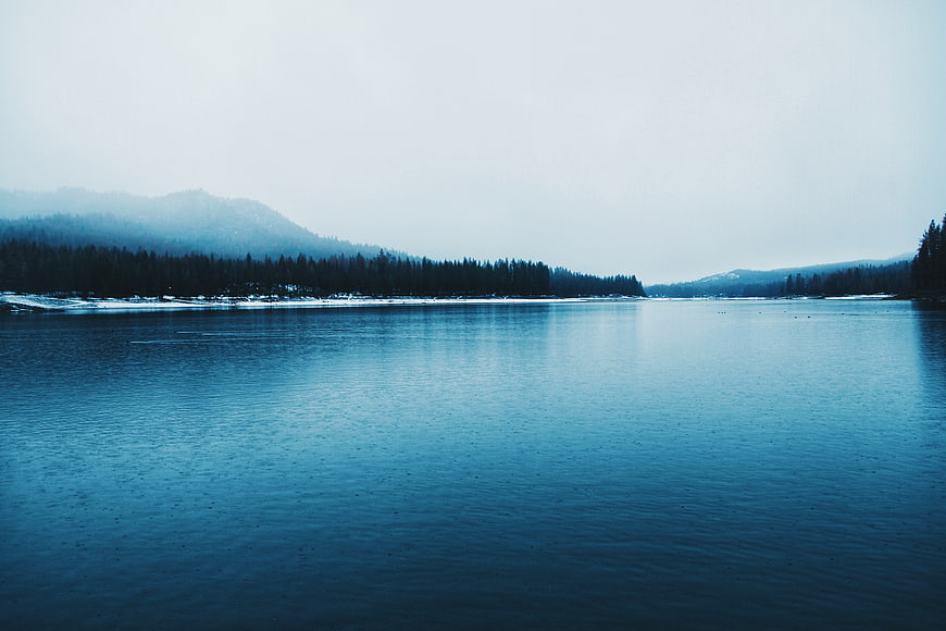 Serene Blue Lake Landscape with Misty Forest Mountains
