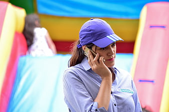 Woman in purple cap talking on smartphone at colorful event